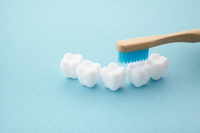 Child's hand with toothbrush and white platic tooth on blue background